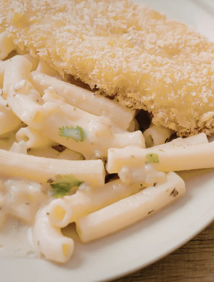 Prato farto de frango frito dourado servido ao lado de macarrão com queijo cremoso